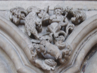 A carving of a monkey king listening to a goat playing the fiddle