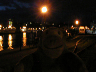 Mr Monkey walking along the quayside at night