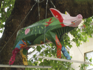 A pig painted as a rain forest hanging from a tree
