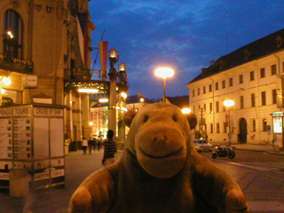 Mr Monkey looking  past the Municipal House at night