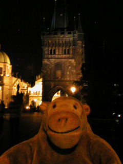 Mr Monkey looking at the tower on the Charles Bridge at night
