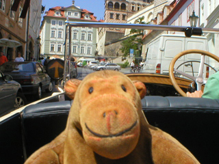 Mr Monkey driving up Nerudova in a vintage car