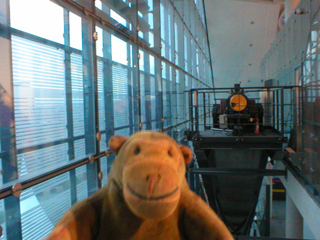 Mr Monkey looking at the motor at the top of the Urbis glass elevator