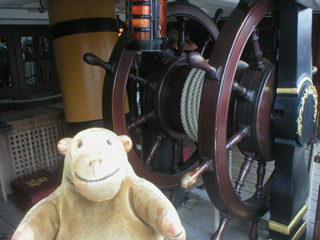 Mr Monkey looking at HMS Victory's ship's wheel
