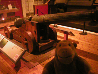 Mr Monkey looking at a bronze cannon on a replica carriage