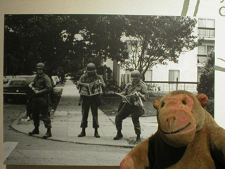 Mr Monkey looking at a photo showing National Guardsmen reading the Black Panther newspaper