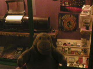 Mr Monkey looking at a cabinet of things relating to mechanical music
