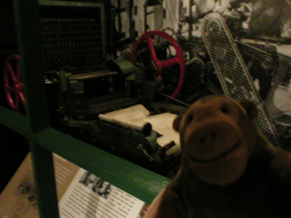 Mr Monkey looking at a machine to make piano rolls