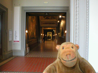 Mr Monkey looking down a long corridor at the V&A