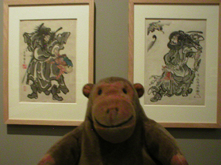 Mr Monkey looking at prints of Shoki the Demon Queller by Kawanabe Kyosai