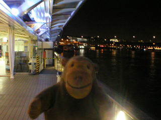 Mr Monkey looking downriver from the Embankment pier at night