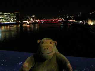 Mr Monkey looking at London Bridge from Tower Bridge in the dark
