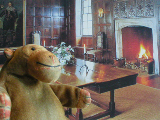 Mr Monkey in front of a postcard of the Great Chamber of Sutton House