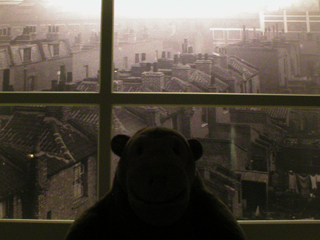 Mr Monkey looking through a window at a picture of pre-war Hackney