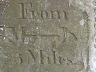 The carving on the milestone at Wood Lanes