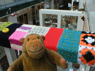 Mr Monkey looking at yarnbombing on the bannisters