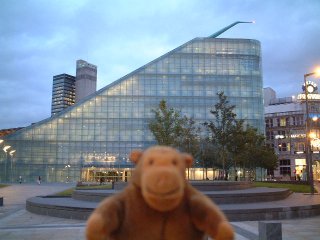 Mr Monkey with wedge shaped glass museum behind him