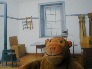 Mr Monkey in front of a picture of the recreation of the Shaker room