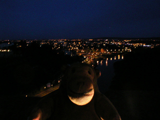 Mr Monkey looking at Bristol at night from the centre of the Clifton suspension bridge