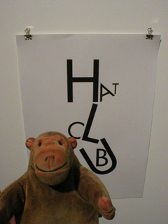 Mr Monkey looking at a poster for the Hat Club