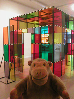 Mr Monkey looking at a plexiglass cabin by Daniel Buren