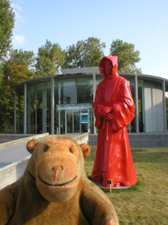 Mr Monkey looking at a tall red monk