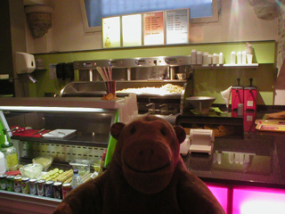 Mr Monkey looking at the counter and frying equipment in the frituur