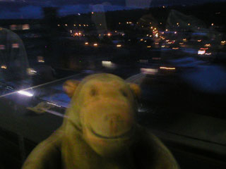 Mr Monkey looking at the lights of a town from the train