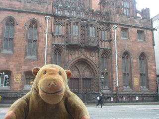 Mr Monkey looking across Deansgate at the front of the John Rylands Library