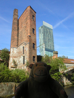 Mr Monkey looking at an old ruined warehouse and the new Beetham Tower