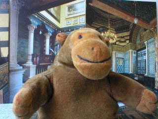 Mr Monkey in front of postcards of the Arab Hall and the blue tiled staircase