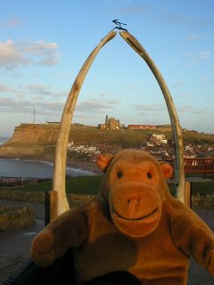 Mr Monkey in front of an arch made from a whale's jawbone