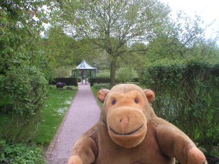 Mr Monkey on a path, with a gazebo behind him
