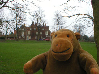 Mr Monkey on a path, with a mansion in the distance