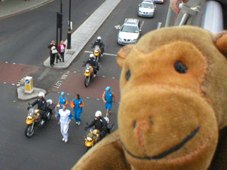 Mr Monkey watching a runner with the Olympic Flame
