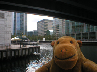 Mr Monkey under a railway bridge, looking at shiny buidlings