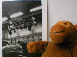 Mr Monkey with a Robert Frank picture of a Detroit car factory