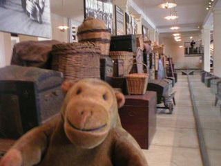 Mr Monkey in front of a collection of luggage from around the world