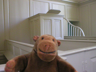Mr Monkey looking at a box pew and the chapel pulpit
