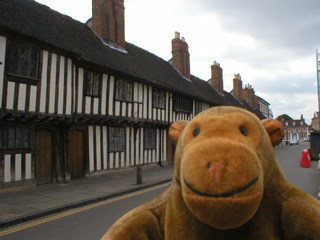 Mr Monkey outside a row of almshouses