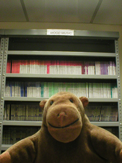 Mr Monkey in front of shelves labelled Mood Music