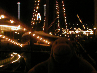 Mr Monkey next to a ship covered in lights