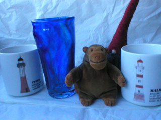 Mr Monkey with two lighthouse mugs, a blue glass, and a tomte