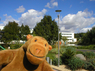 Mr Monkey looking at the Goliath building from the top of the bus