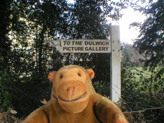 Mr Monkey in front of sign pointing to Dulwich Picture Gallery
