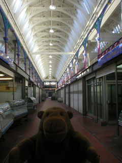 Mr Monkey looking at a row of butcher's stalls