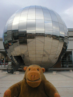 Mr Monkey in front of a large silver globe