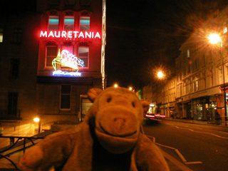 Mr Monkey walking up Park Street at night