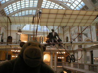 Mr Monkey looking at a replica Bristol Box Kite aircraft