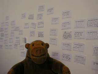 Mr Monkey looking at a wall of postcards